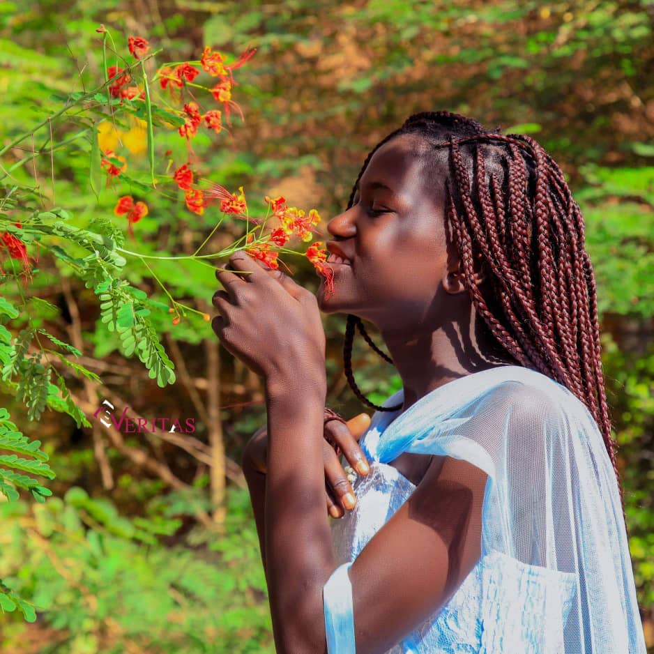 Comedian Kiden | Confident South Sudan Award-Winning Comedian 3 youngster smells flowers with beautiful African hairstyle