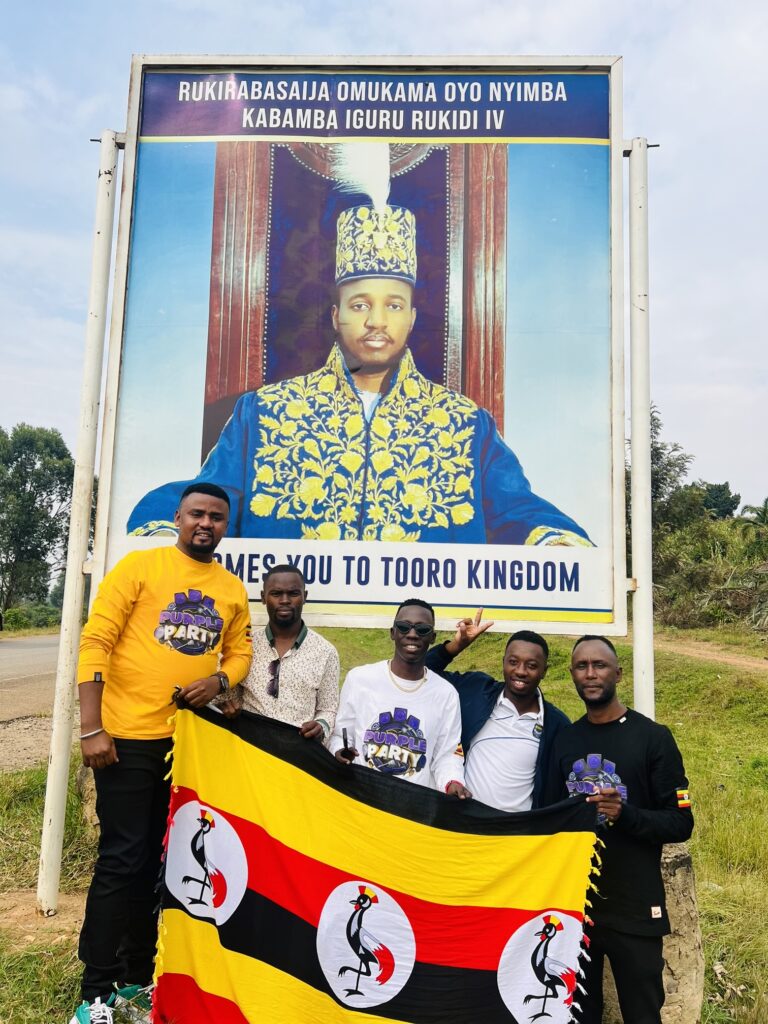 Douglas Lwanga and team in Fort Portal in front of a sign post showing King Oyo of Tooro