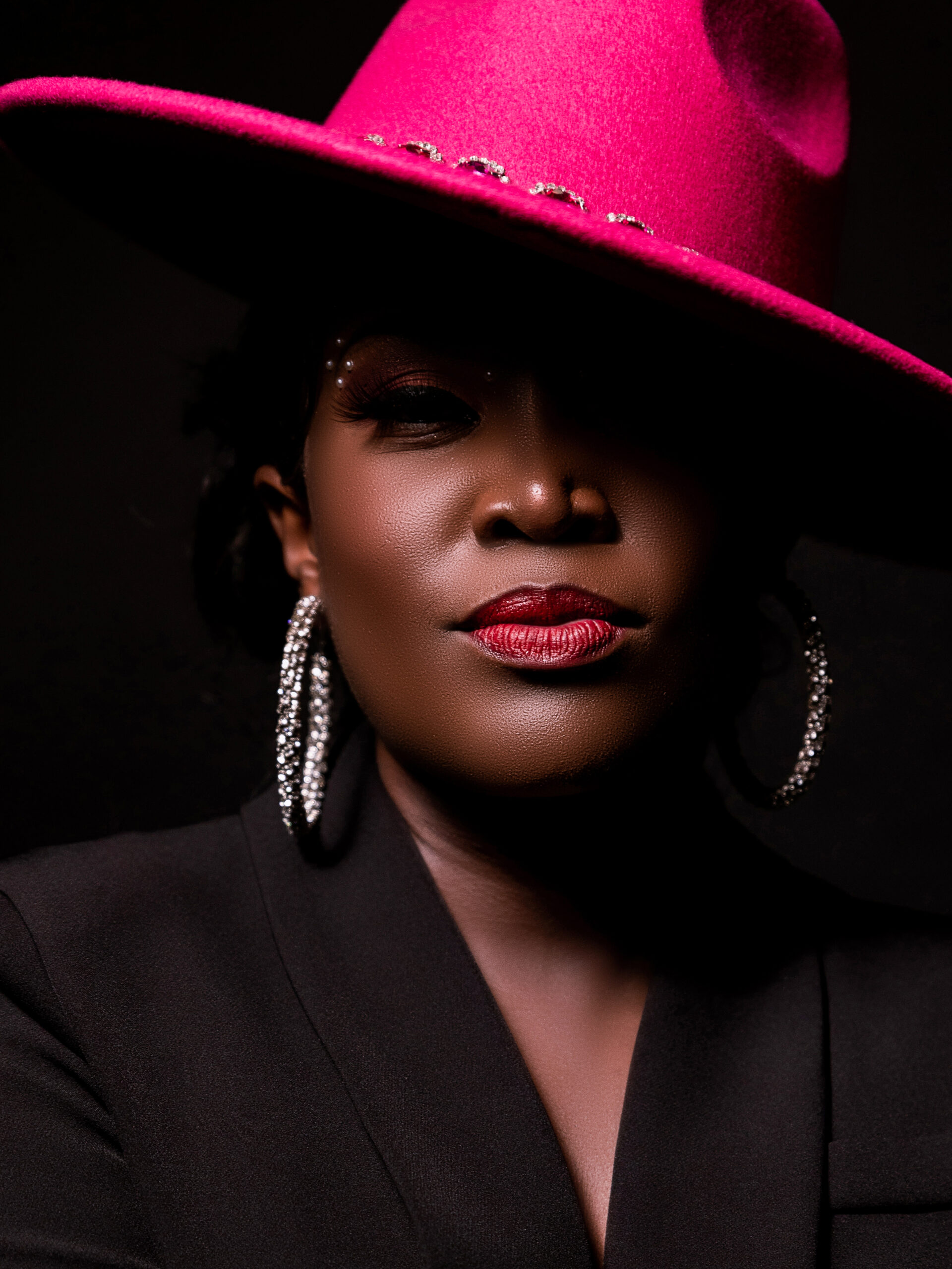 Naira Ali in black with pink hat